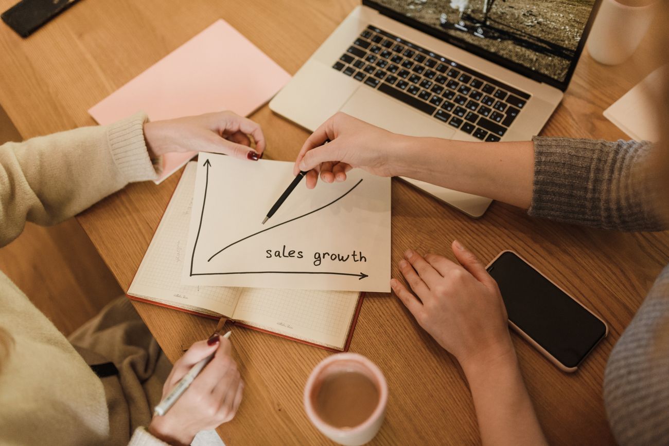 Two marketers planning lead generation growth with performance charts and a laptop